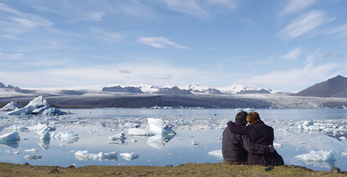 Paar sitzt vor zugefrorenem Bergsee
